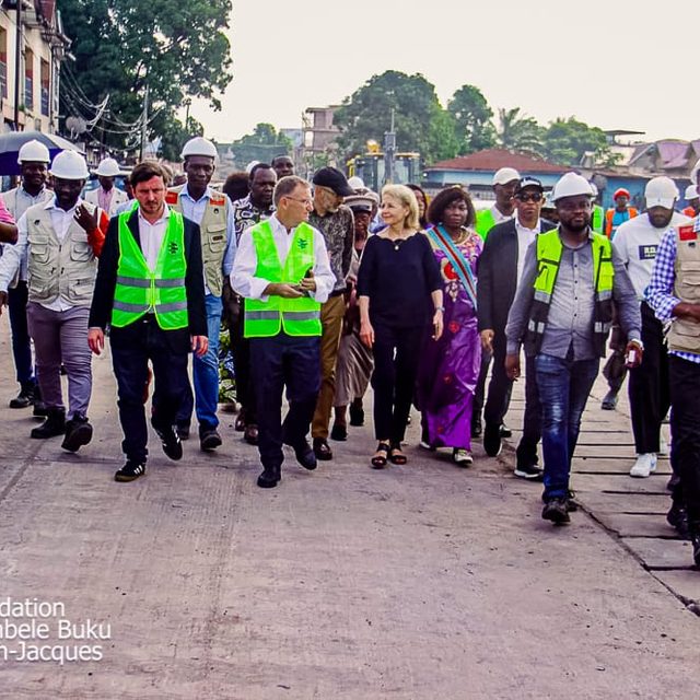 Membres de la Fondation et habitants en gilets de chantier, marchant ensemble sur une avenue de Limete
